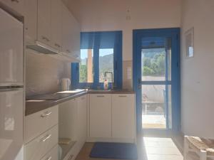 a kitchen with white cabinets and a blue window at Louloudi in Kato Alepochori