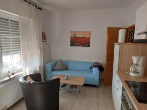 a living room with a blue couch and a table at Ferienanlage Blinkfuer in Dornumersiel