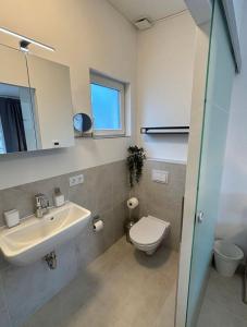 ein Badezimmer mit Waschbecken, Toilette und Spiegel in der Unterkunft Ostseebad Göhren Fewo 4 mit Südterrasse in Baabe