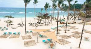 a beach with chairs and palm trees and the ocean at Gerbi's Condoplace at Oceanway Residences in Sampong