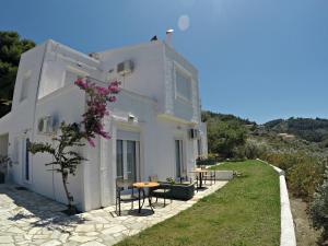 ein weißes Haus mit einem Tisch und Stühlen davor in der Unterkunft Villa Ariadni in Skiathos-Stadt