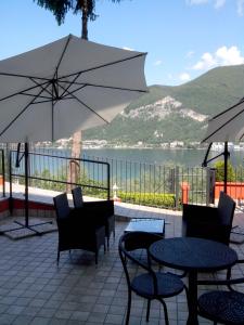 un patio con tavoli, sedie e ombrellone di Hotel Empire Resort a Iseo