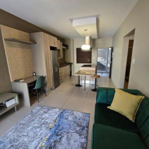 a living room with a green couch and a kitchen at Atrium Oasis, Sandton in Johannesburg