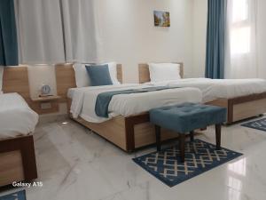 塞拉莱نجم صلاله的一间卧室设有两张床和蓝色凳子。