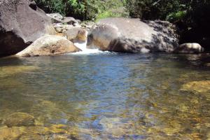 a stream of water with rocks and a waterfall at Gran Camping Cabanas da Fazenda in Visconde De Maua