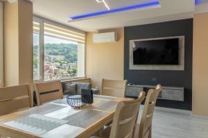 a dining room with a table and chairs and a television at Апартамент Балкан Тауър in Gabrovo