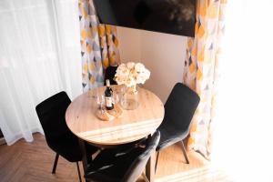 a dining room table with black chairs and a vase of flowers at Młynarska Dolina A in Koniaków