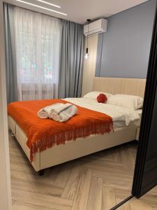 una camera da letto con un letto con una coperta arancione e una finestra di Designer apartment opposite the Airport a Almaty