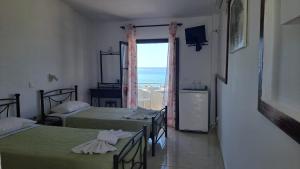 a room with two beds with a view of the ocean at Kefalonia Beach Hotel & Bungalows in Lixouri