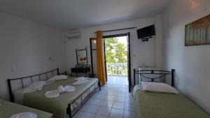 two beds in a room with a window at Kefalonia Beach Hotel & Bungalows in Lixouri
