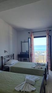 a bedroom with two beds and a view of the ocean at Kefalonia Beach Hotel & Bungalows in Lixouri