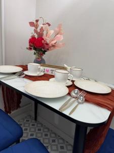 a table with white plates and a vase of flowers at Designer apartment opposite the Airport in Almaty