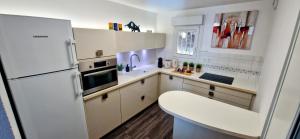 a kitchen with white cabinets and a white refrigerator at LE DOMAINE DU GOLFE, Vue Exceptionnelle, Standing, 2 parkings, Climatisation, Piscine, Tennis in Sète +9 photos