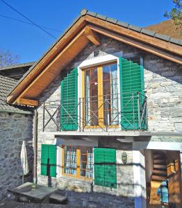 una casa con persiane verdi e balcone di Rustico Camelia by HolAp SA a Gordevio