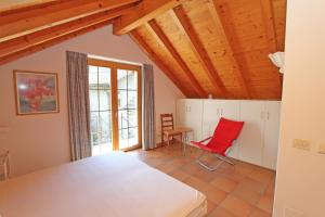 una camera da letto con un letto e una sedia rossa di Rustico Camelia by HolAp SA a Gordevio