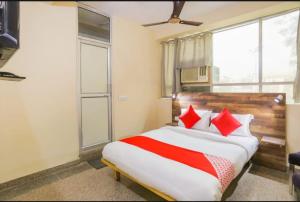 a bedroom with a large bed with red pillows at solstice suites in Faridabad