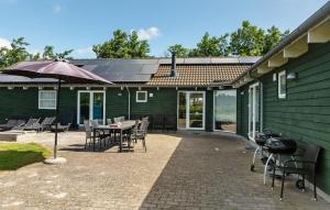 a patio with a table and chairs and an umbrella at Pet Friendly Home In Idestrup With Sauna in Marielyst +14 photos
