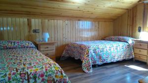 a bedroom with two beds and wooden walls at Apartaments Pont Romànic in Espot