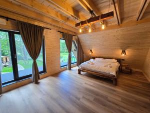 a bedroom with a bed and large windows at Căsuța din Zăvoi in Sânâteşti +24 photos