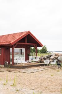 a pavilion with white chairs and a house at Kabe Beach House in Kaberneeme