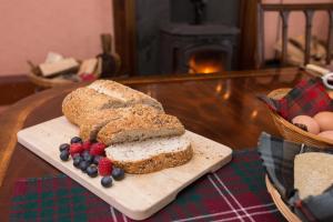 a loaf of bread and berries on a cutting board at Holly Lodge in Strathpeffer