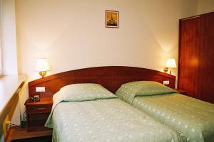 a bedroom with a bed and a night stand with two lamps at ET Nocleg in Kalisz