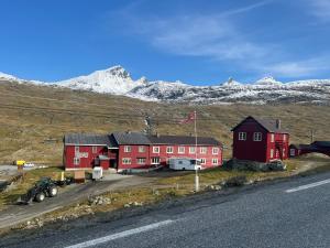 a red house on a hill with mountains in the background at Krossbu in Boverdalen