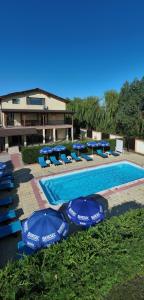 a swimming pool with blue umbrellas and lounge chairs at Casa Vlad in Murighiol