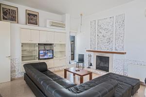 sala de estar con sofá de cuero negro y chimenea en Napa Nissi House, en Ayia Napa