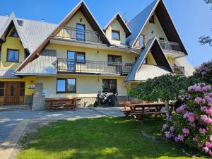 a large house with picnic tables in front of it at Dom Wypocz Pod Litwinką Apartamenty in Białka Tatrzańska +88 photos