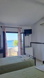 a bedroom with two beds and a view of the ocean at Kefalonia Beach Hotel & Bungalows in Lixouri