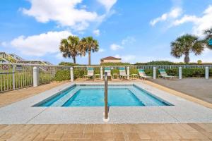 a swimming pool with chairs and a fence at Caribbean Resort 501A - Link To The Beach in Navarre