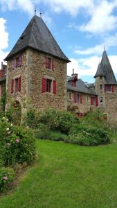 ein altes Steingebäude mit roten Fenstern und Blumen in der Unterkunft Chateau de Bellefond in Lagraulière