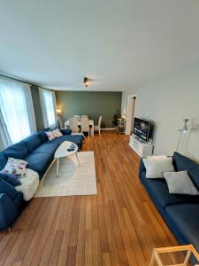 a living room with blue couches and a television at Central and spacious 3-bedroom apartment in Mandal