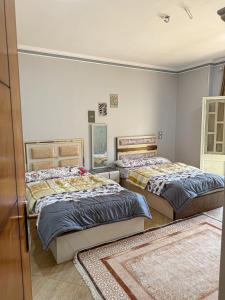 two beds in a room with two rugs at ElShrouk United Agency in Bayāḑ al ‘Arab