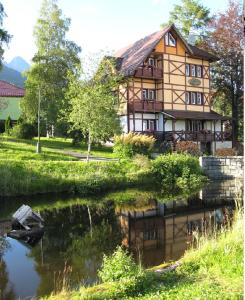un bâtiment à côté d'une rivière avec une maison dans l'établissement Penzión Villa Mon Ami, à Nový Smokovec