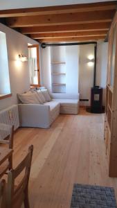 a living room with a white couch and a wooden floor at Sunny and cosy holiday apartment in the Dolomites in Pianaz