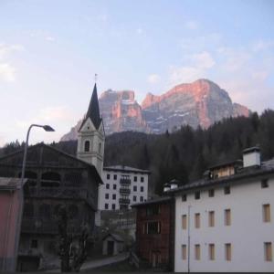 a church and buildings with a mountain in the background at Sunny and cosy holiday apartment in the Dolomites in Pianaz
