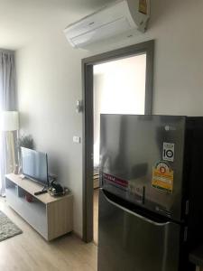 Il comprend une cuisine équipée d'un réfrigérateur et d'une table avec une télévision. dans l'établissement Home hugs, à Bangna