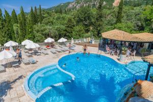 a pool at a resort with people sitting around it at Paleokastritsa Palace - Adults Only in Paleokastritsa