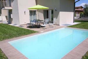 a swimming pool with chairs and a table and an umbrella at Le Golfette - Ville al Golf in Manerba del Garda