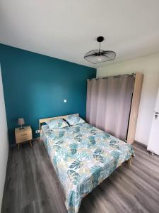 a bed in a bedroom with a blue wall at Appartement cosy au calme in Hasparren