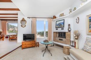 Una sala de estar con televisión y chimenea. en Cala Nostra- Roca Rosa, en Tamariu