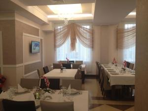 a restaurant with white tables and chairs and a chandelier at Hotel-Restaurant Oscar in Piatra Neamţ