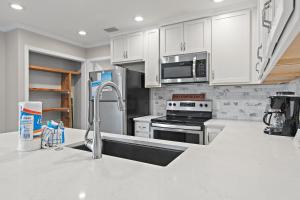 a kitchen with white cabinets and a stainless steel sink at Capri by the Gulf 122 in Destin +24 photos
