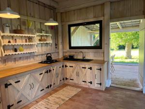 a kitchen with wooden cabinets and a large window at Wigierska Piertówka 2 in Suwałki