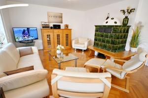 a living room with white furniture and a flat screen tv at Chiemsee-Ferienhaus Schlegel in Breitbrunn