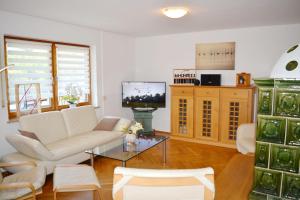 a living room with a white couch and a tv at Chiemsee-Ferienhaus Schlegel in Breitbrunn