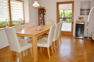 a dining room with a wooden table and white chairs at Chiemsee-Ferienhaus Schlegel in Breitbrunn