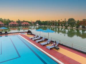 a pool at a resort with chairs and umbrellas at Sterling Lake Palace Alleppey in Alleppey